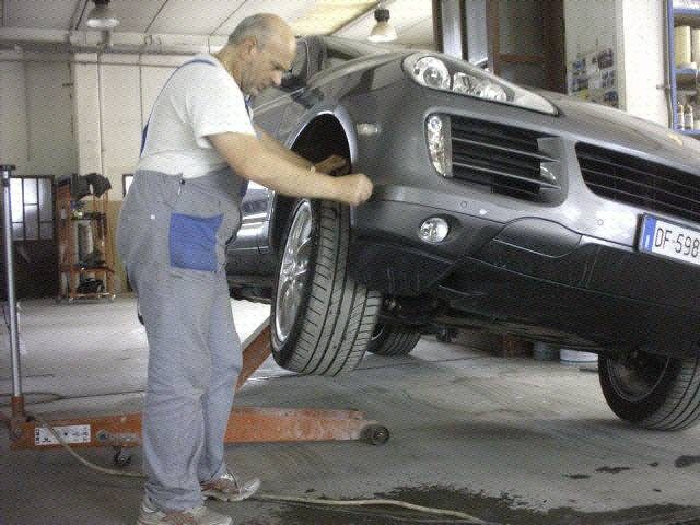 Un meccanico controlla la ruota anteriore di una Porsche Cayenne sul ponte